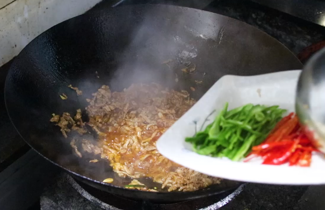 青红辣椒炒软后把胡萝卜放下去翻炒，然后把芹菜和木耳、豆干依次放下去翻炒至断生。